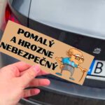 Držanie samolepky s nápisom "Pomaly a hrozne nebezpečný".