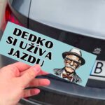 Nálepka "Dedko si užíva jazdu" na aute.