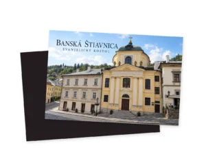 Grafická ilustrácia žltého priečelia evanjelického kostola so stĺpmi a kupolou v radovej zástavbe Banskej Štiavnice.